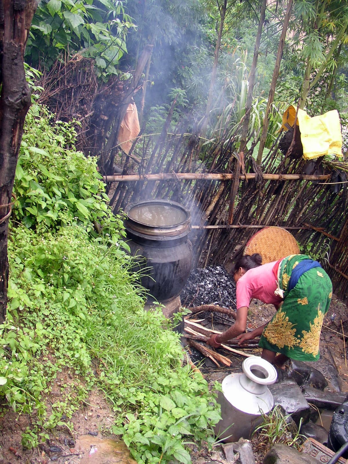 A woman tending a wood fire under a still, at a village distillery in Nepal